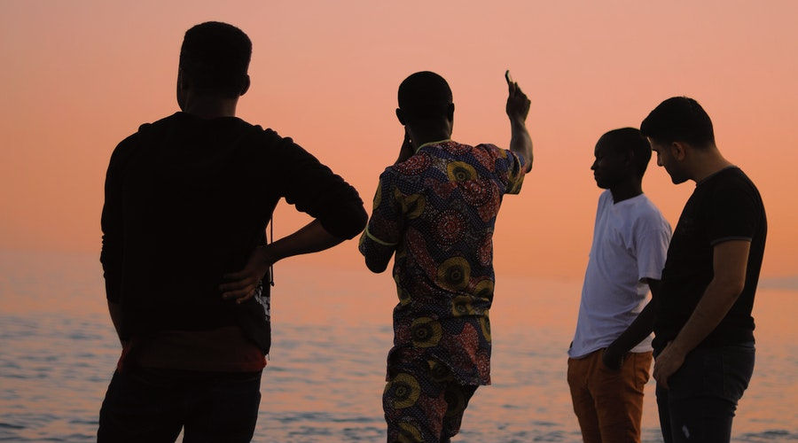 Men on a beach at sunset. | Learn language with study abroad.